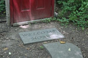 a stone mat with "Welcome Home" carved in it in front of a red door