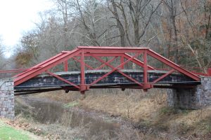 a red steel bridge over a canal with low water