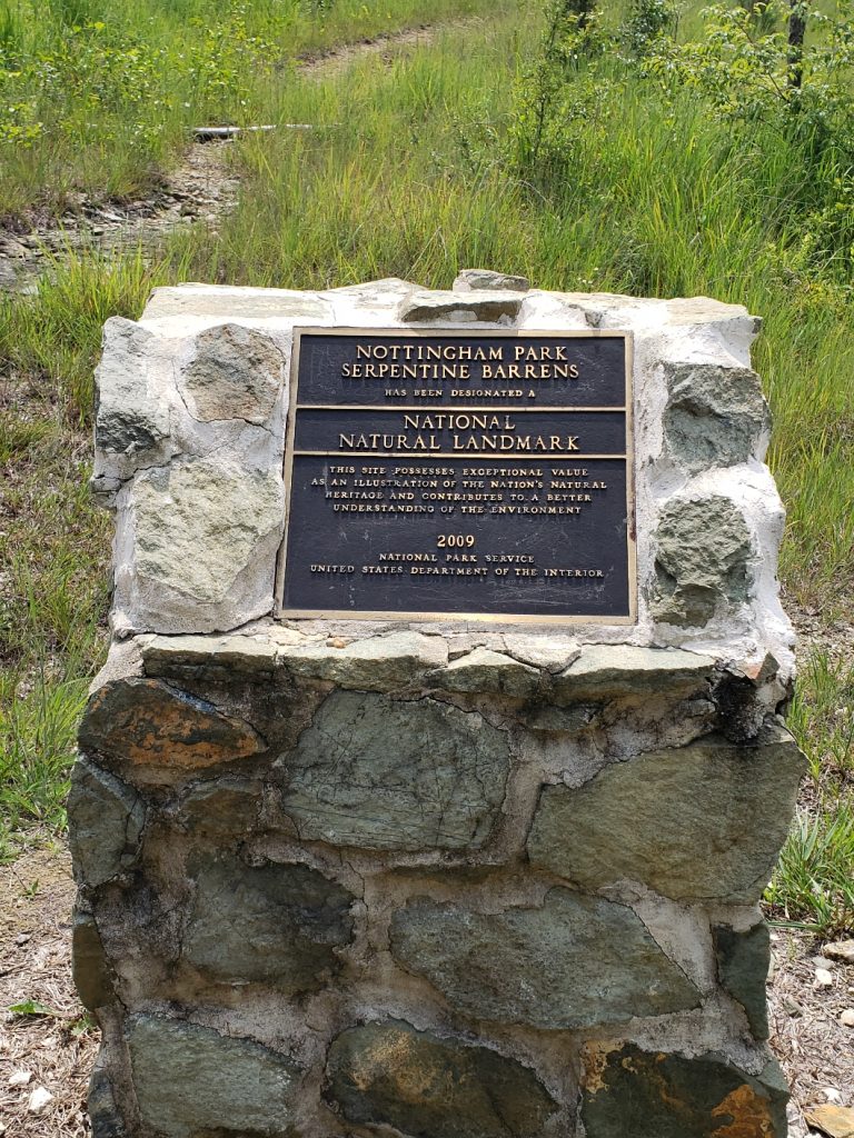 a plaque on a stone base: "NOTTINGHAM PARK SERPENTINE BARRENS has been designated a NATIONAL NATURAL LANDMARK 

This site possesses exceptional value as an illustration of the nation's natural heritage and contributes to a better understanding of the environment
2009 
National Park Service
United States Department of the Interior