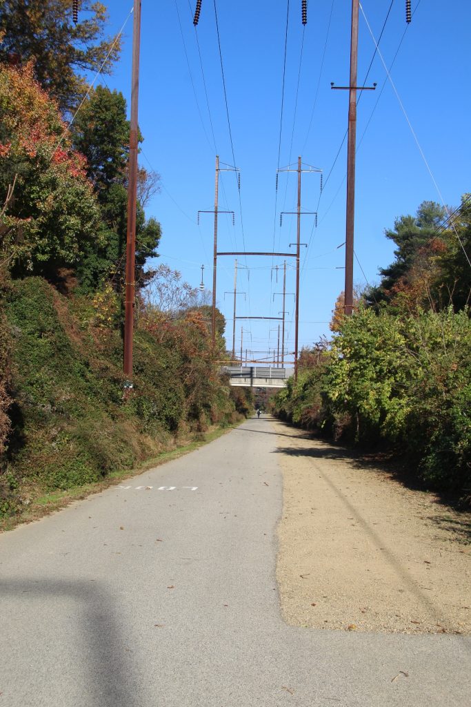 a paved path beneath power lines - an old railbed